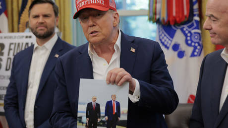 US President Donald Trump holds a photograph of himself with Russian President Vladimir Putin in Alaska, Washington, DC, August 22, 2025.