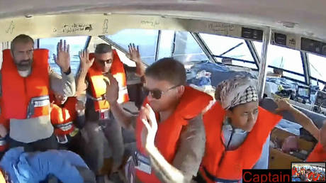 Activists aboard a Global Sumud Flotilla vessel raise their hands as Israeli naval forces intercept the flotilla en route to Gaza in the Mediterranean Sea, October 2, 2025.