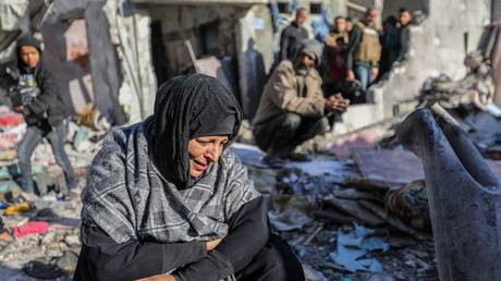FILE PHOTO: A woman sits amongst damaged homes caused by Israeli air strikes in Rafah, Gaza.