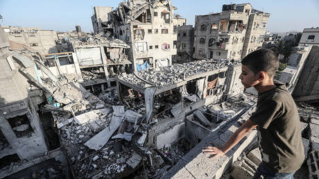 A child looks over to the destroyed building in Bureij, Gaza, after an Israeli attack  on October 20, 2025.  © Moiz Salhi/Anadolu via Getty Images